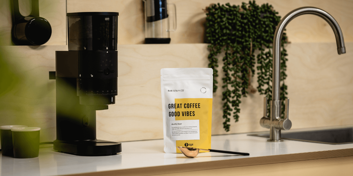 ground coffee in a sealed bag next to an electric grinder